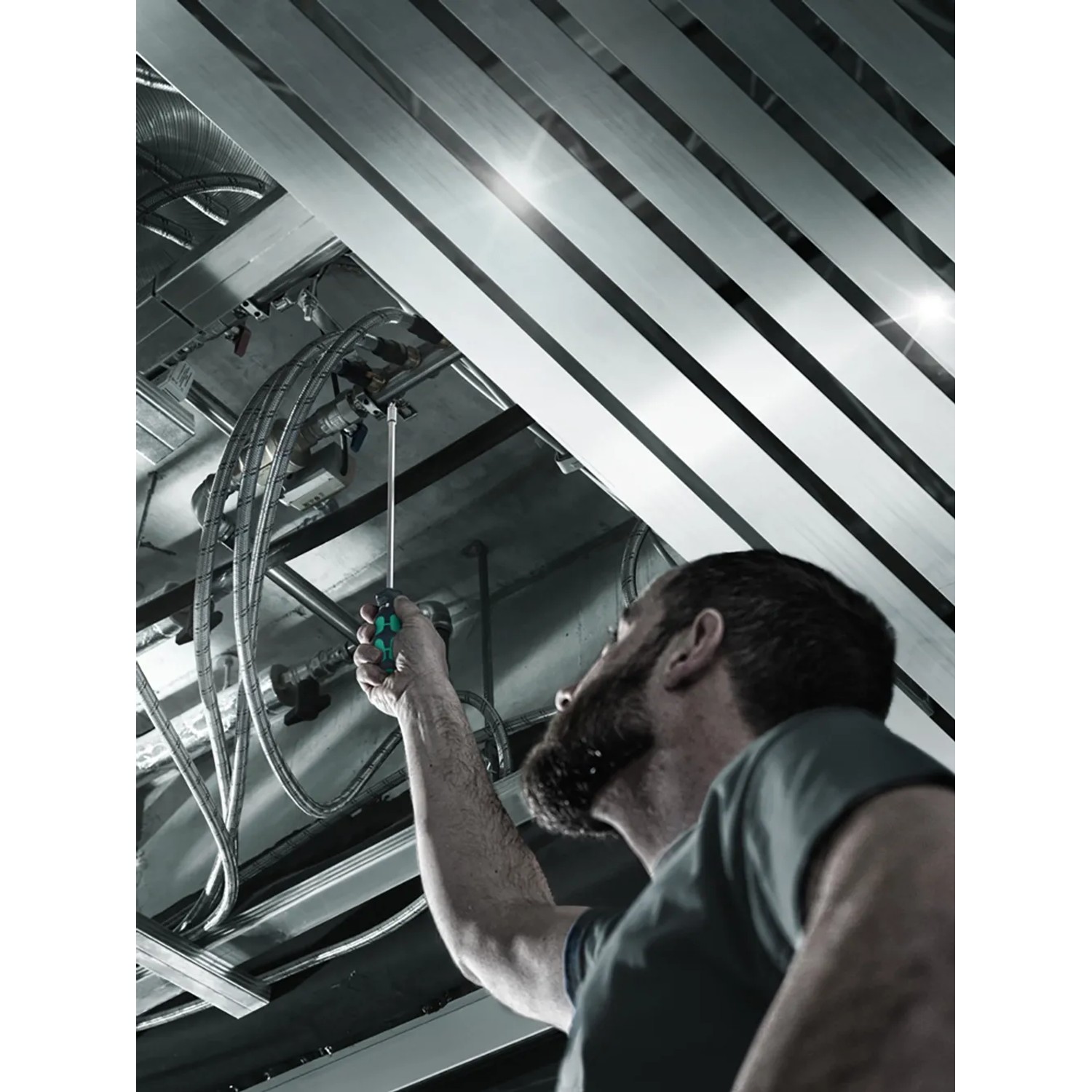Mann arbeitet mit Wera Werkzeug-Set Kraftform Kompakt Schraubendreher an Deckeninstallation.