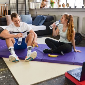 Ein Paar entspannt auf lila und beiger faltbarer Turnmatte im Wohnzimmer. Vielseitige Trainingsmatte für Sport & Gymnastik.