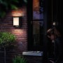 Anthrazitfarbene LED-Außenwandleuchte Arbour mit Sensor an einer Backsteinwand.