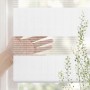 Weißes Doppelrollo mit transparenten und blickdichten Streifen. Eine Hand demonstriert den regulierbaren Sichtschutz am Fenster.