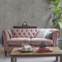Laura Ashley Vliestapete Elderwood Steel im Wohnraum mit Sofa und Tisch.