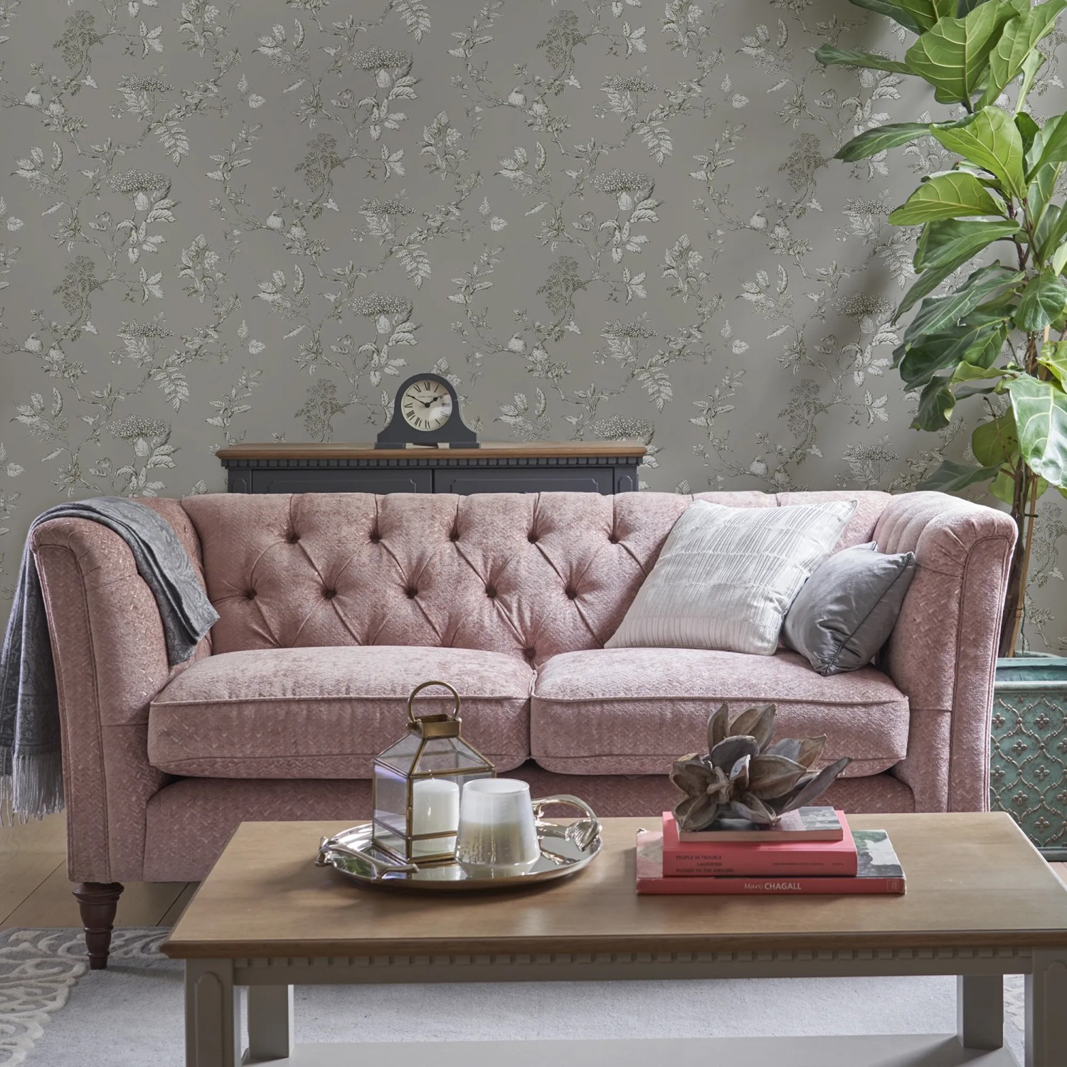 Laura Ashley Vliestapete Elderwood Steel im Wohnraum mit Sofa und Tisch.