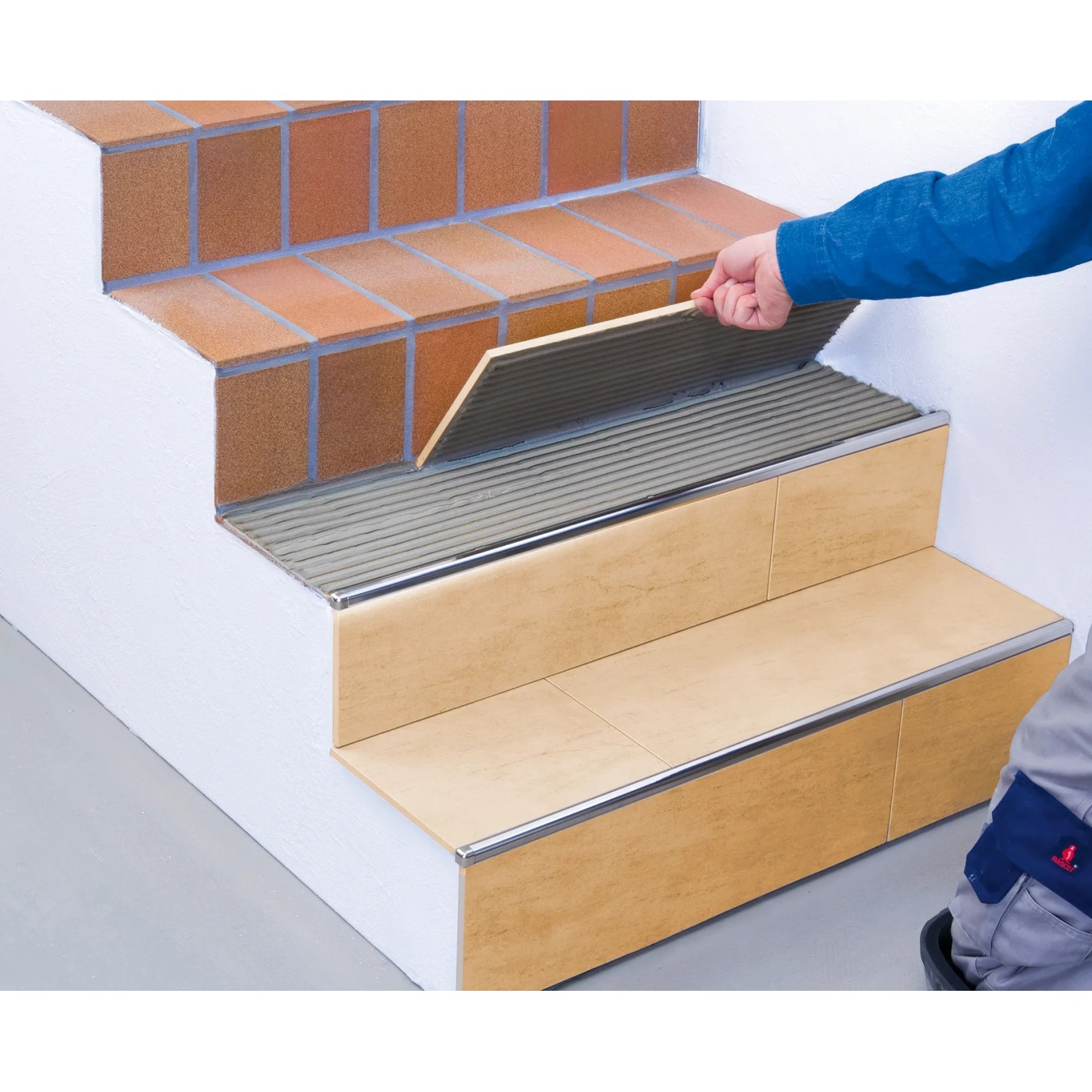 Fliesenleger verlegt Fliesen mit Knauf Flexkleber Schnell Grau auf einer Treppe.