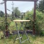 Klappbarer Stehtisch aus Holz und Metall für Garten und Terrasse.