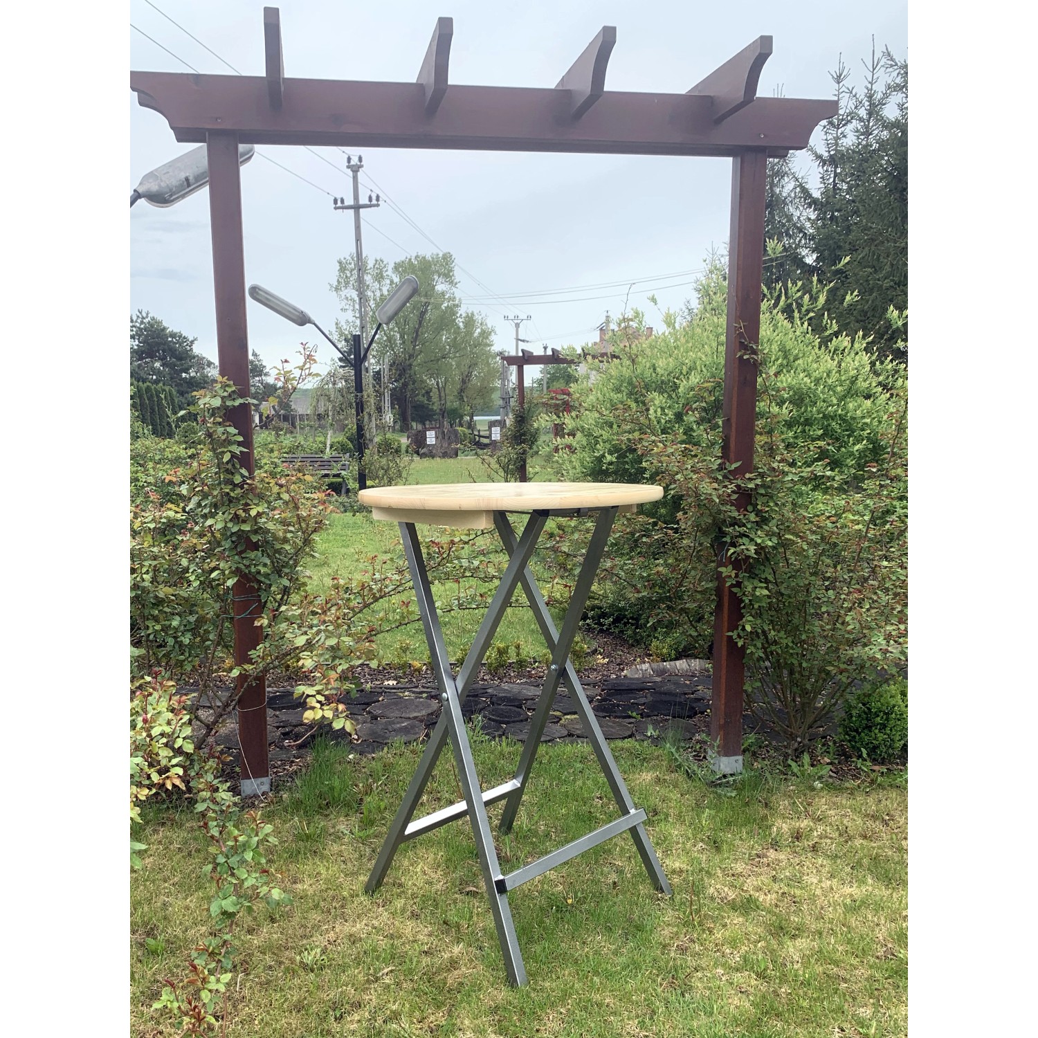 Klappbarer Stehtisch aus Holz und Metall für Garten und Terrasse.