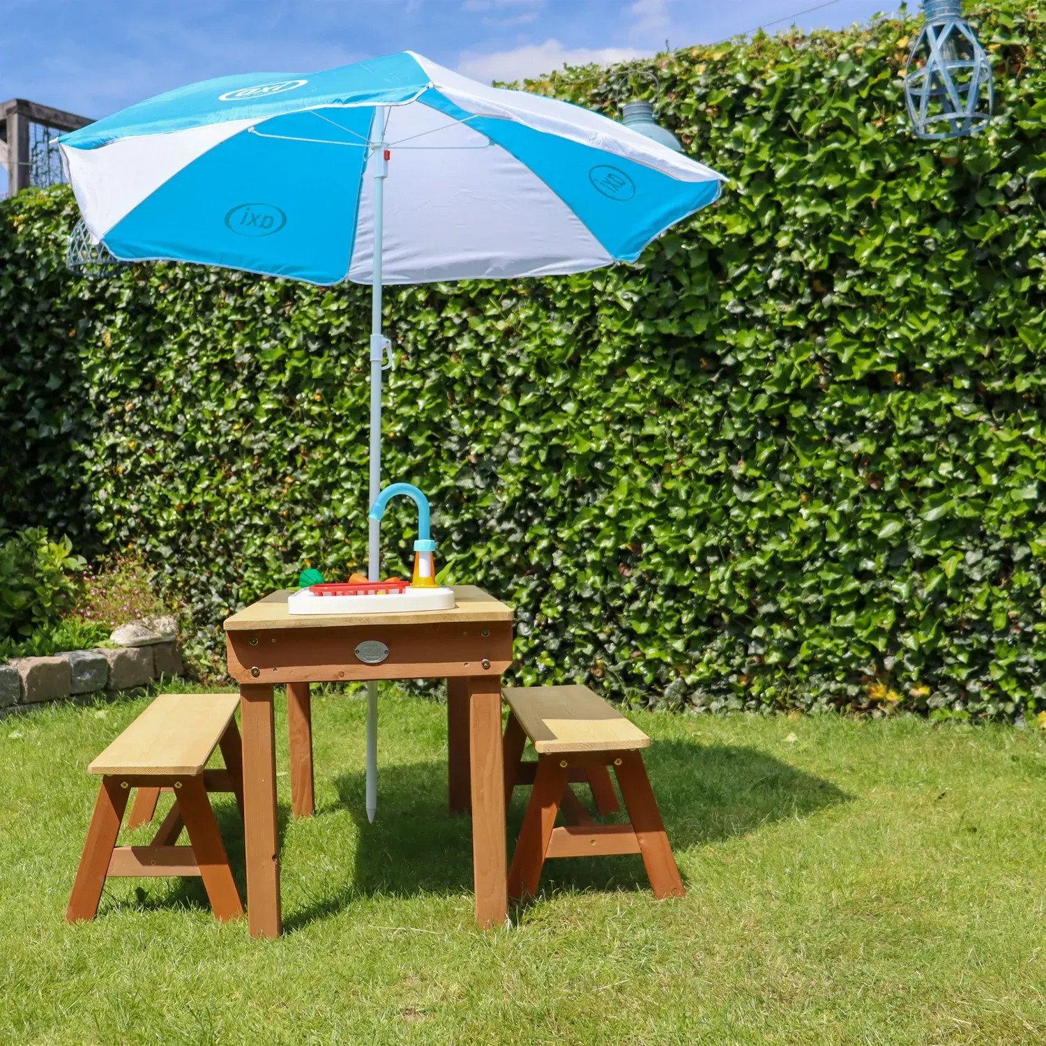 Axi Sand- und Wasser-Picknicktisch Dennis mit Sonnenschirm, blau-weiß, mit Spielküche und Bänken.