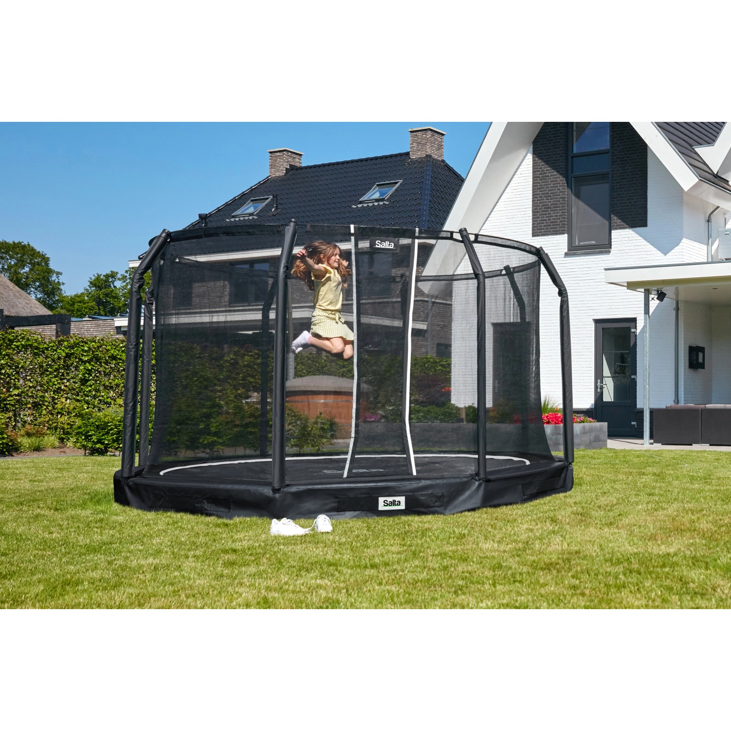 Schwarzes Salta Premium Ground Trampolin (ø 366 cm) mit springendem Kind im Garten.