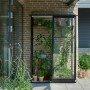 Halls Anlehngewächshaus Qube Lean-to 24, schwarz, mit Pflanzen und Regalen.