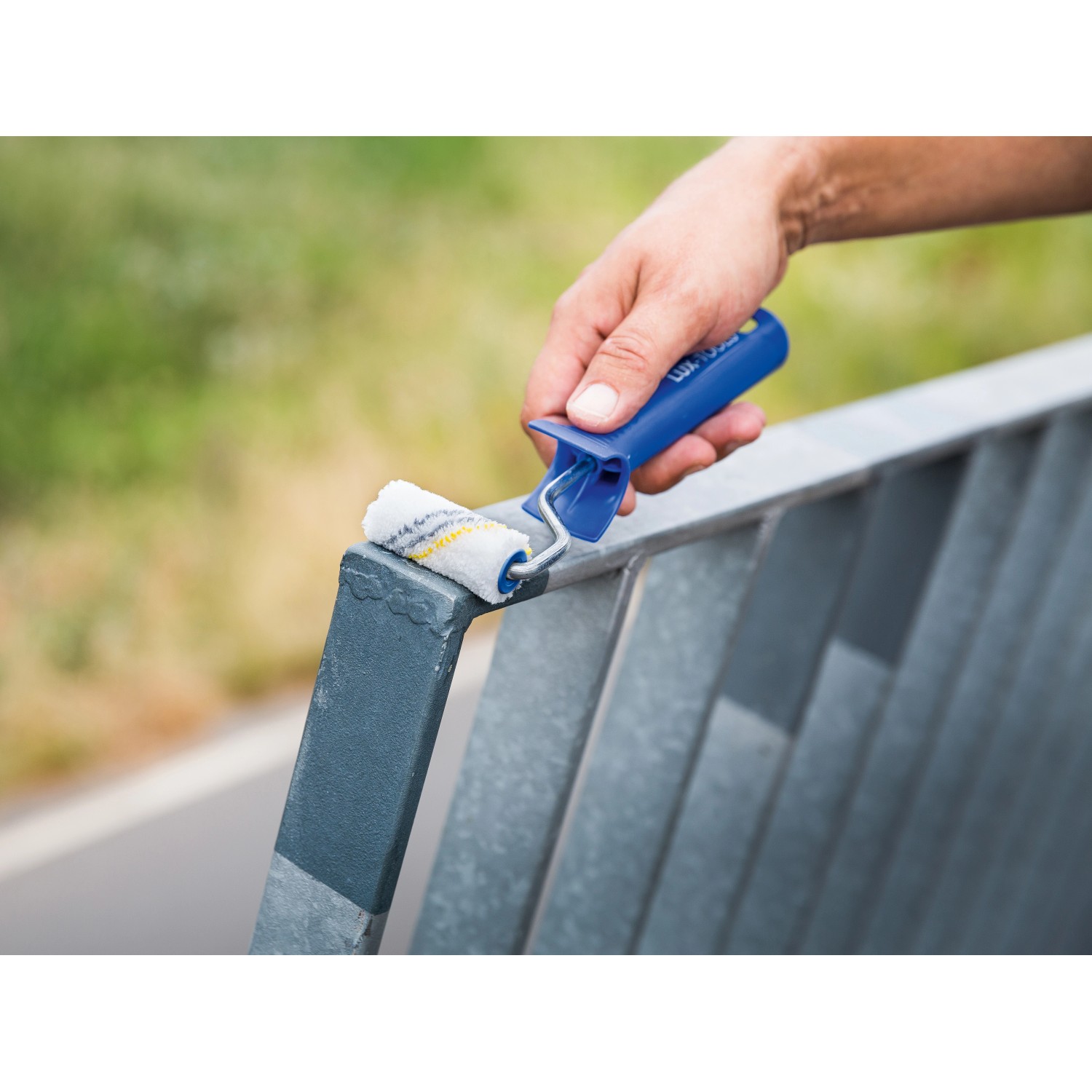 Lackierroller von LUX, 6 cm breit, Mikrofaser, rot-gestreift, beim Lackieren eines Metallgeländers.