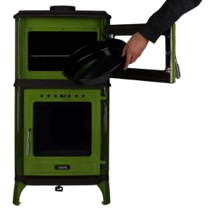 Grüner emaillierter 365 Kaminofen Ferrox 55 Back mit offenem Backrohr; Hand schiebt Backblech hinein. 7 kW Gussofen.