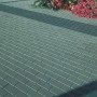 Graue Rechteck-Pflastersteine (20x10x6 cm) auf einer Fläche, mit Blumen am Rand.