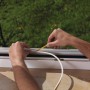 Anbringen einer weißen Tesamoll Fensterdichtung (P-Profil) am Fensterrahmen.
