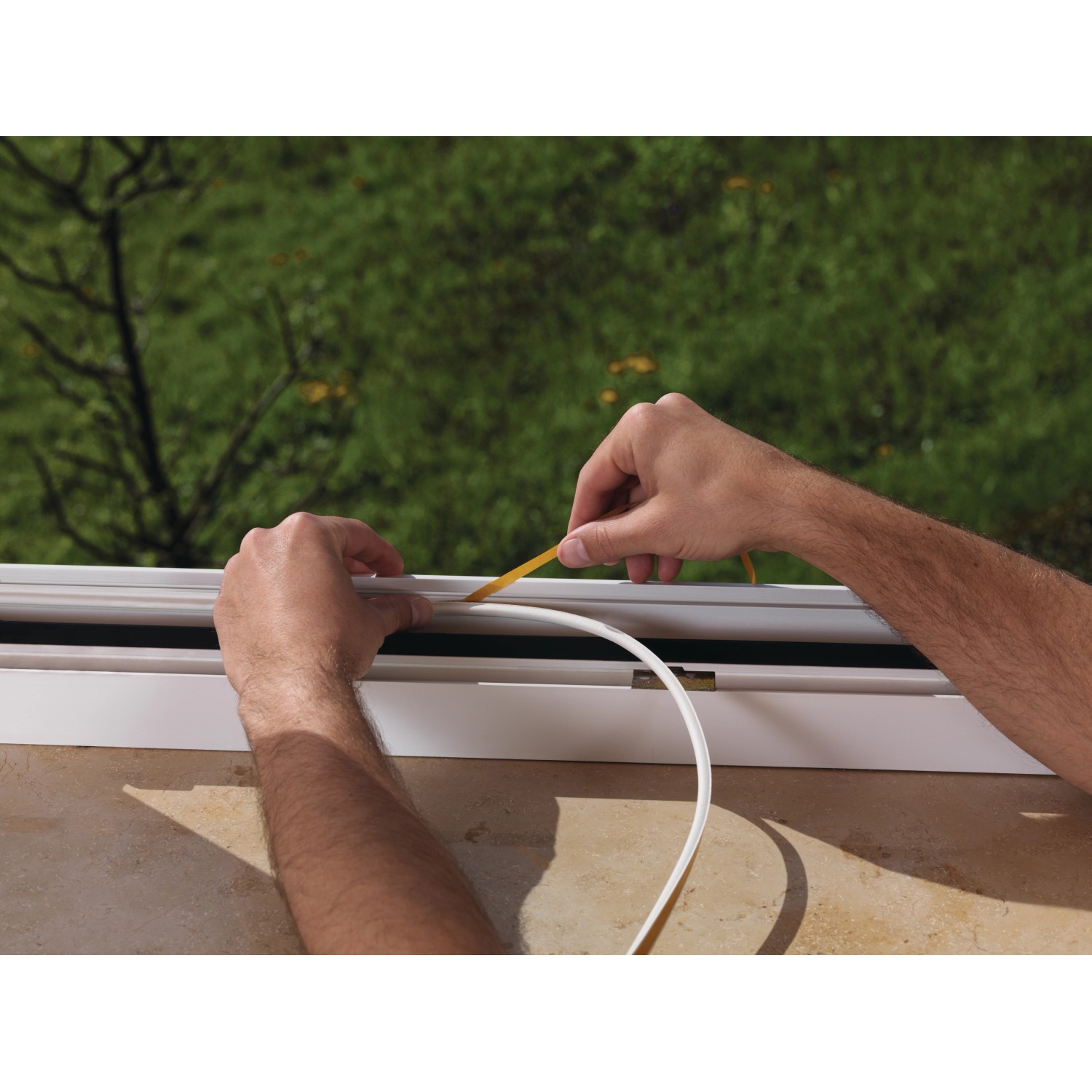 Anbringen einer weißen Tesamoll Fensterdichtung (P-Profil) am Fensterrahmen.