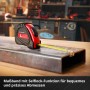 Einhell Rollbandmaß mit rotem Gehäuse und gelbem Band auf einem Werkstück. Teil des Werkzeugkoffer Sets.