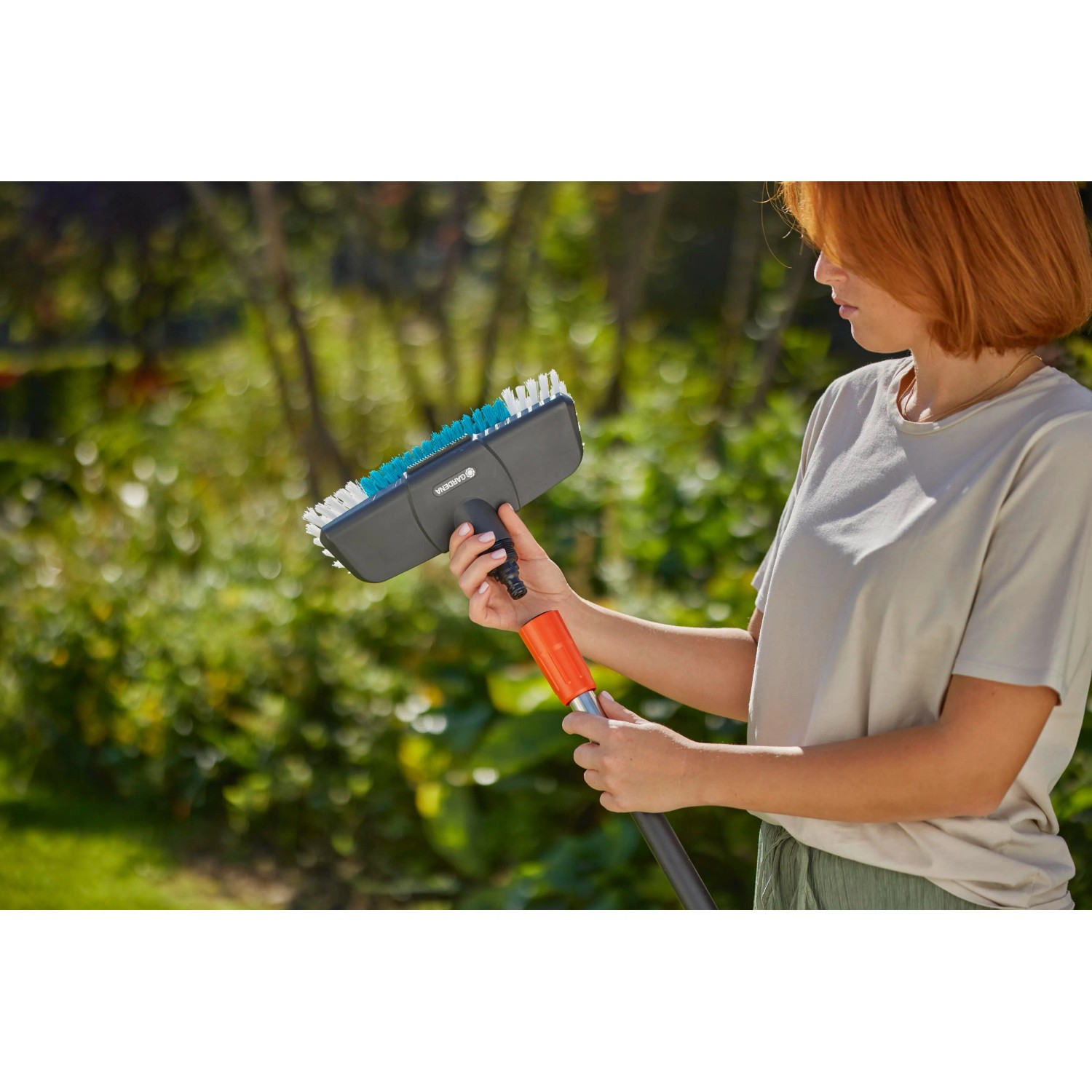 Gardena Cleansystem Stielbürste Hard in Anthrazit mit Frau im Garten. Ideal zur Nassreinigung.