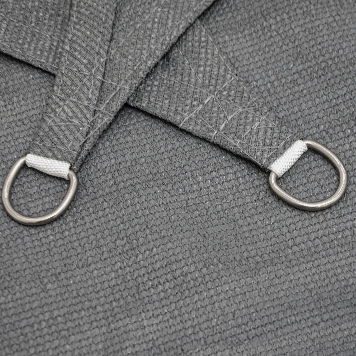 Detailaufnahme eines grauen, viereckigen AMANKA Sonnensegels mit D-Ring Befestigung.