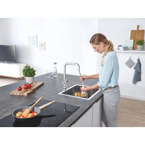 Frau wäscht Gemüse mit Grohe Blue Home Einhebelmischer mit U-Auslauf in Chrom.