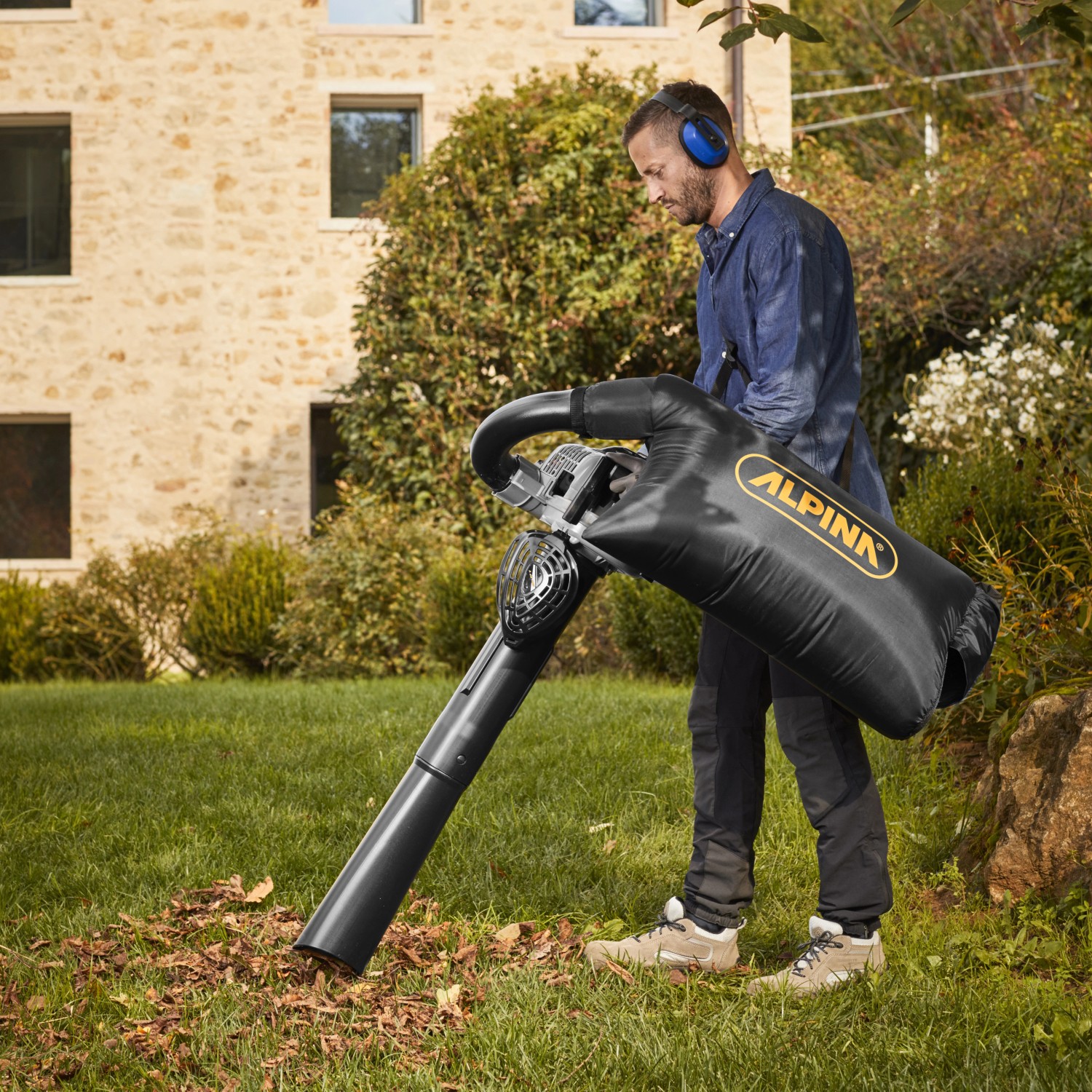 Mann nutzt Alpina Benzin-Laubbläser ABL 27 V mit Saugfunktion im Garten.