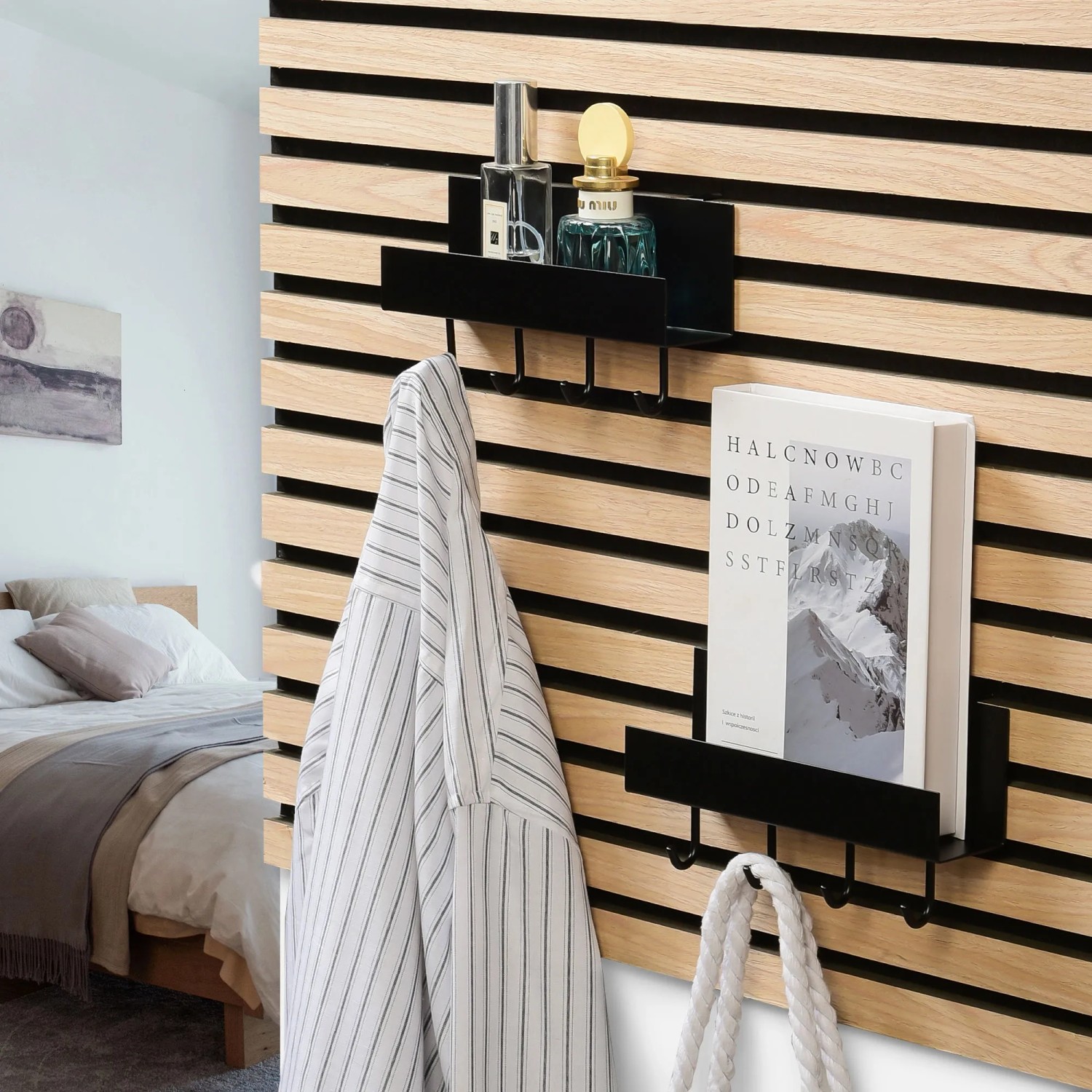 Schwarzes DenPanels Regal mit 4 Stiften an Akustikpaneel mit Deko und Jacke.