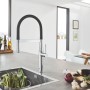 Grohe Essence Küchenarmatur in Chrom mit schwarzem, flexiblem Auslauf vor Küchenspüle.