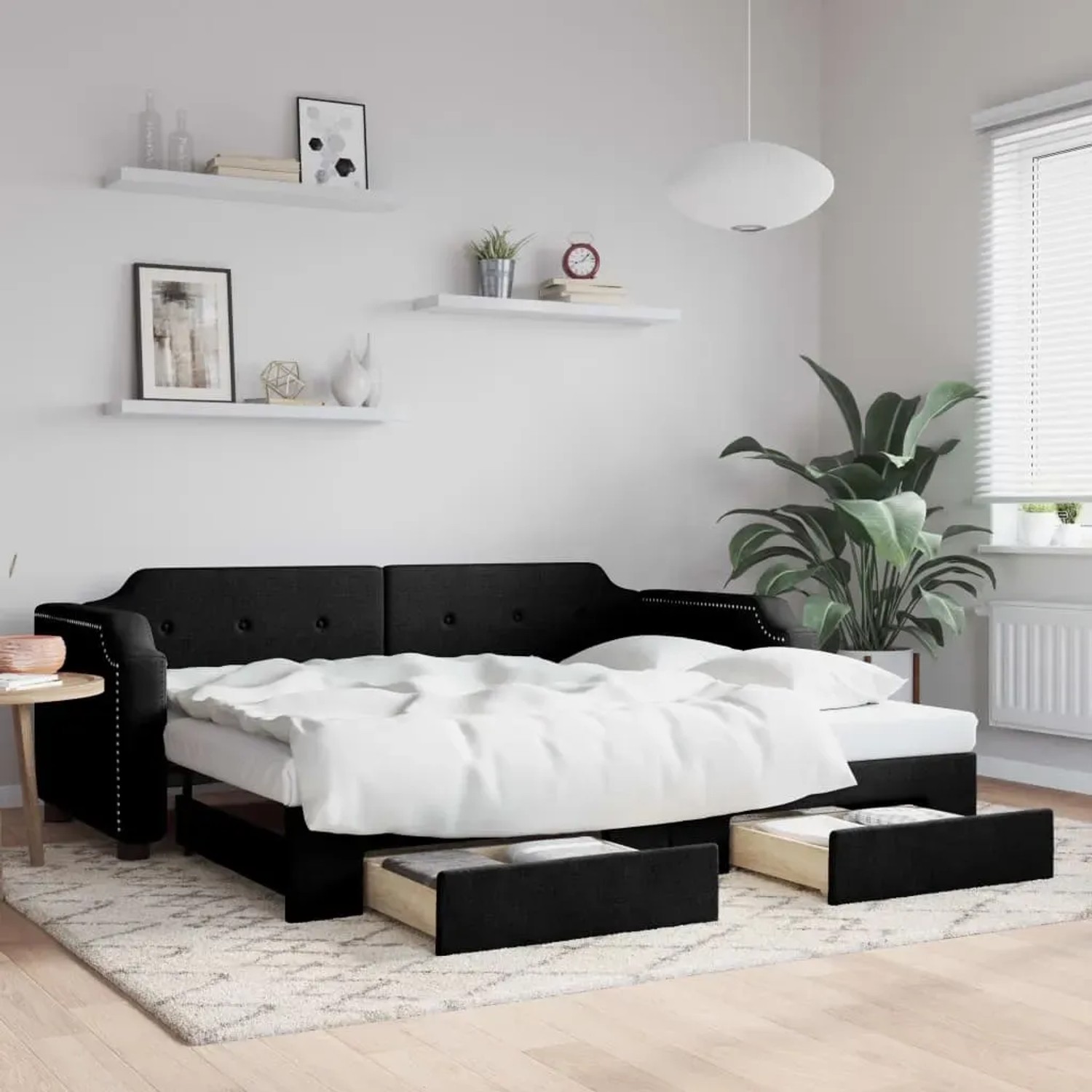 Ausziehbares, schwarzes Tagesbett mit Schubladen (80x200 cm) im Wohnzimmer.