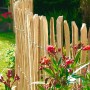 Staketenzaun Haselnuss, 5 m x 0,9 m, im Garten mit Blumen. Naturzaun zur Grundstücksabgrenzung.