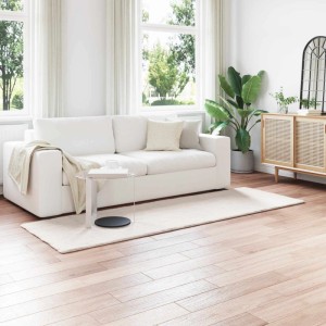 Langer, cremefarbener vidaXL Kunstfell Teppich Olite aus Polyester unter einem Sofa im modernen Wohnzimmer.