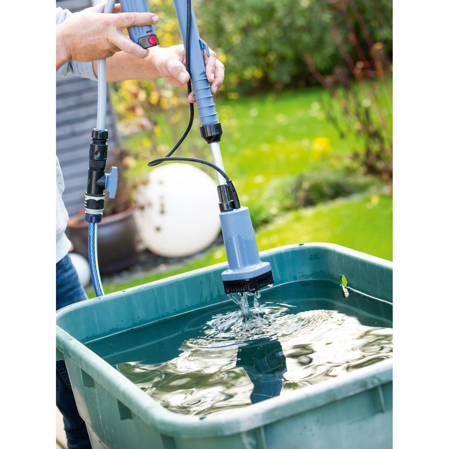 Akku-Regenfasspumpe in Nutzung: Entleeren einer Regentonne zur Gartenbewässerung.