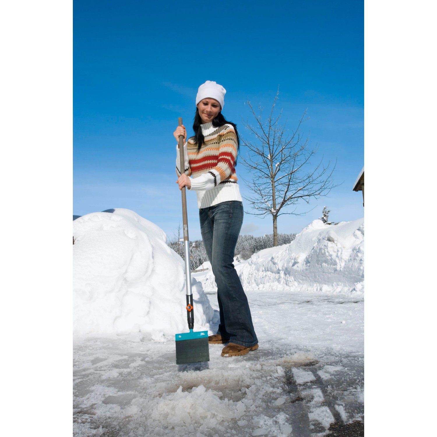 Frau benutzt Gardena combisystem Holzstiel 130 cm mit Schneeschieber zum Schneeräumen.