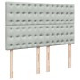 Hellgraues Boxspringbett Kopfteil aus Samt mit Knopfheftung und Holzfüßen.