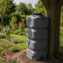 Grauer, quadratischer KMND 750L Wassertank aus PE im Garten neben Baum. Für Regen- & Trinkwasser.