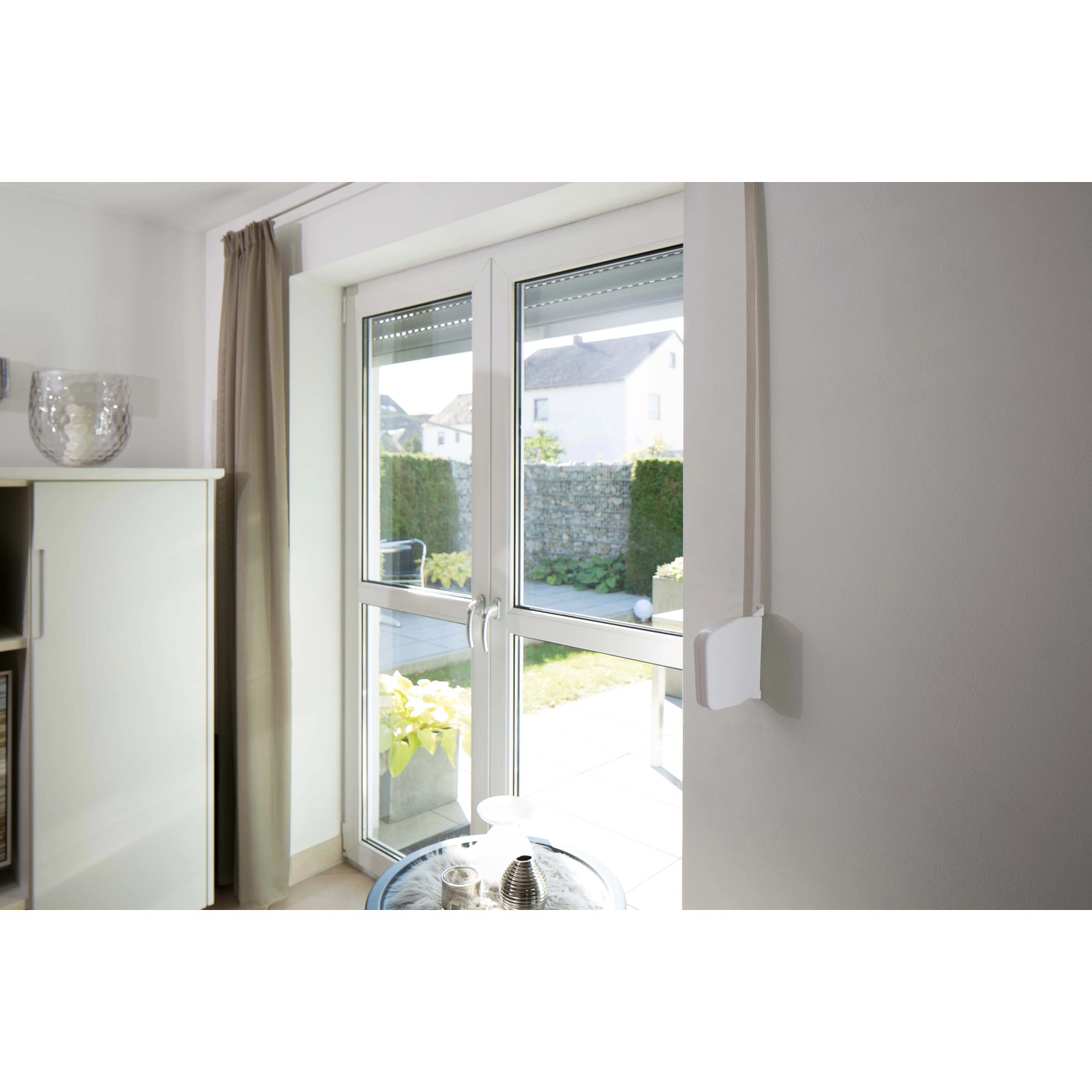 Schellenberg Aufschraubwickler Mini, schwenkbar, weiß, mit Rollladengurt an einem Fenster montiert.