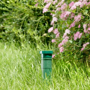 Windhager Wühlmaus-Vertreiber Classic 3 Star im Rasen vor blühendem Strauch.