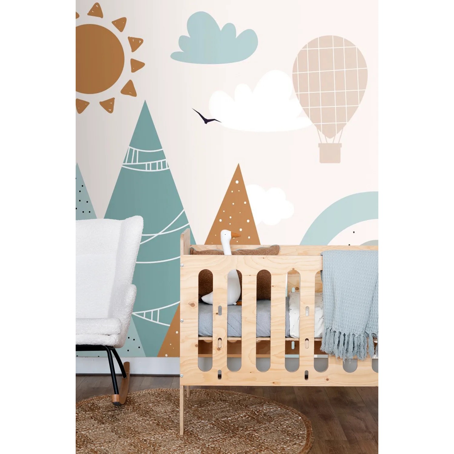 ESTAhome Fototapete Berge in Grau-Blau und Orange im Kinderzimmer mit Babybett und Schaukelstuhl.