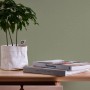 A.S. Création Vliestapete Greenery Uni, olivgrüne Struktur, mit Pflanze und Büchern auf Tisch.