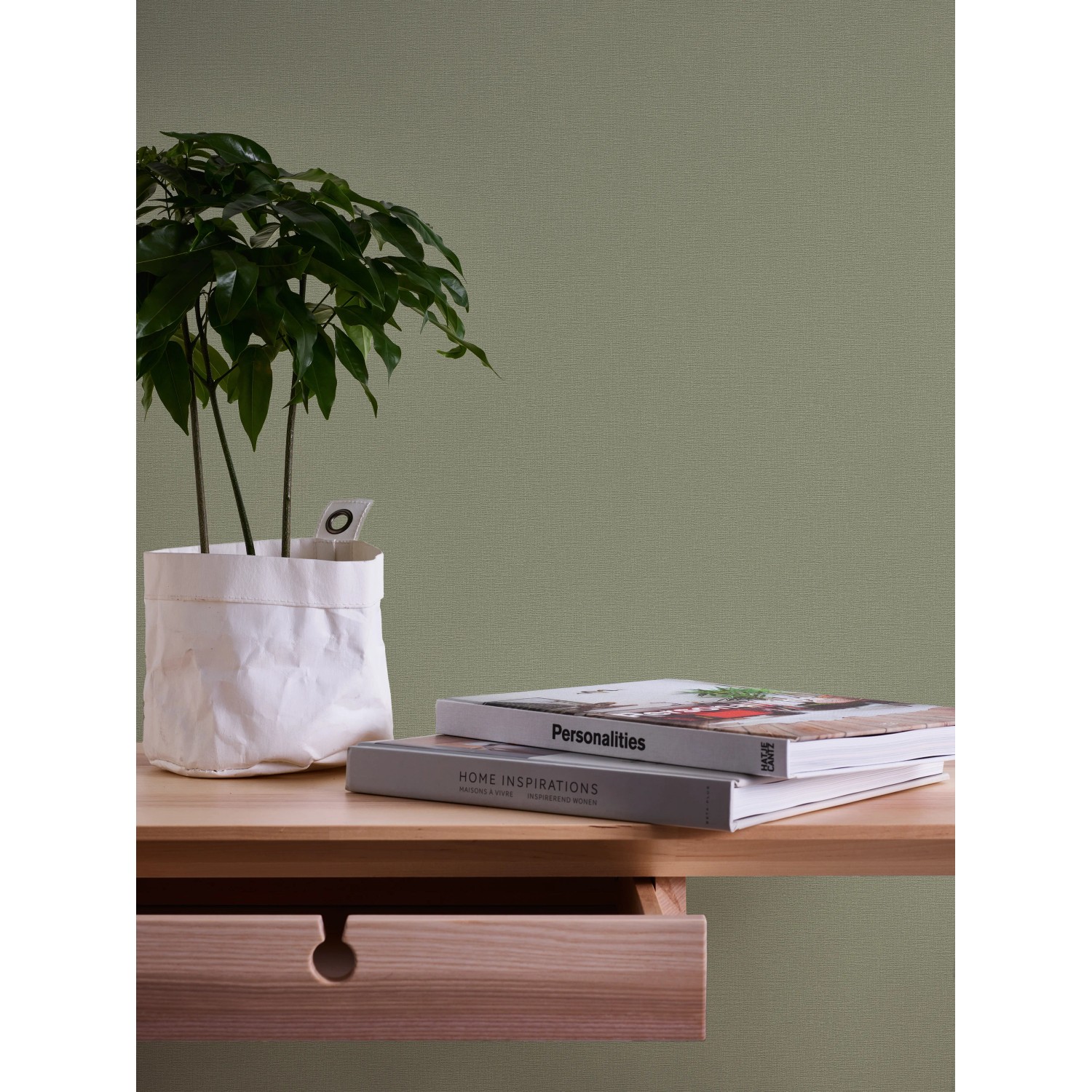 A.S. Création Vliestapete Greenery Uni, olivgrüne Struktur, mit Pflanze und Büchern auf Tisch.