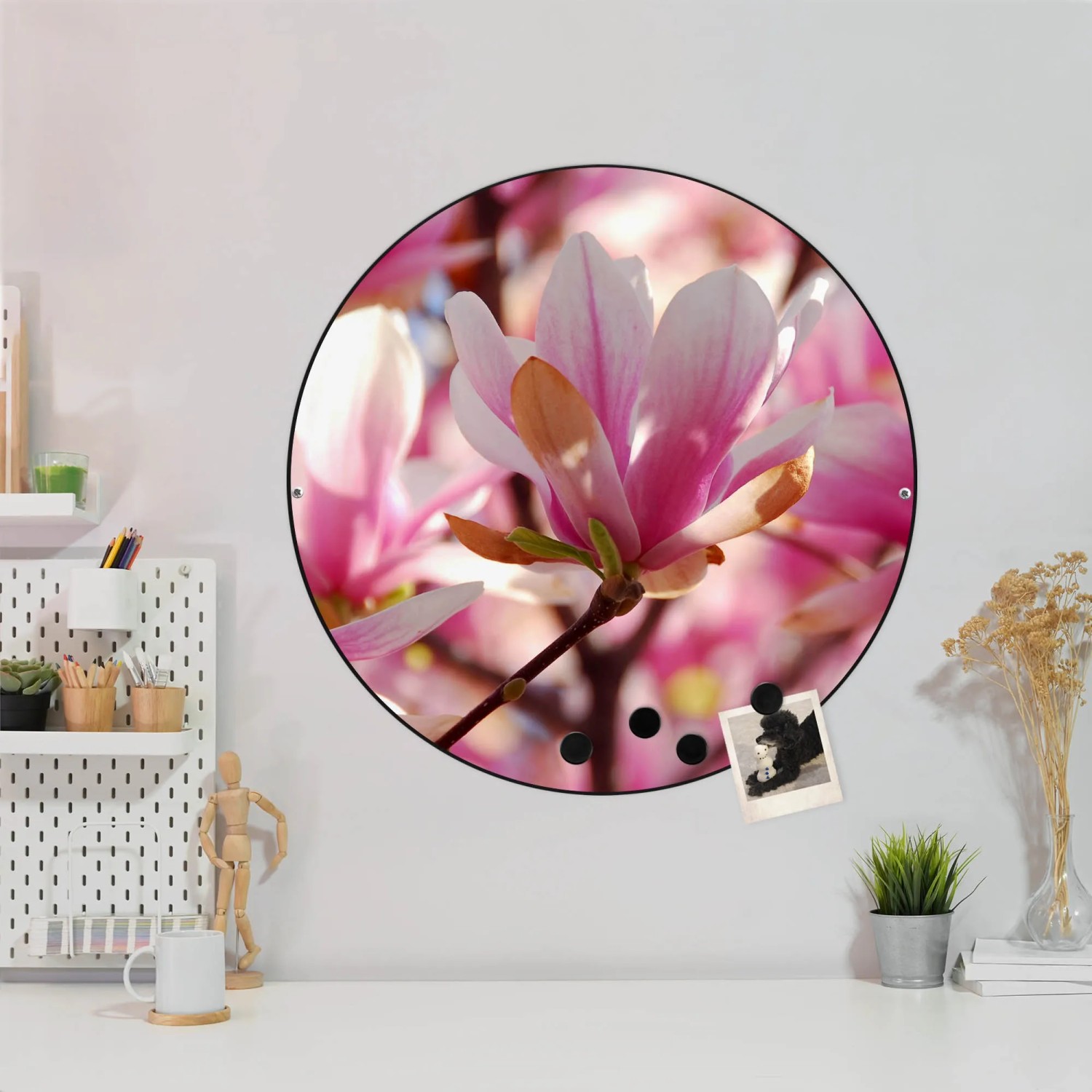 Runde, schwarze Magnettafel mit Magnolien-Motiv als Wanddekoration.