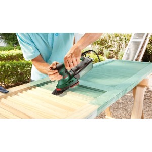 Mann schleift mit Bosch Multischleifer PSM 200 AES grüne Farbe von Holzfensterladen ab. Präzise Schleifmaschine für Holz.