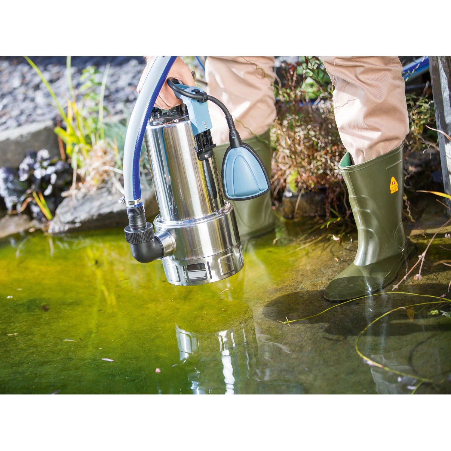 Tauchpumpe 1100 W TPS 21000/E im Einsatz am Teich. Elektro-Pumpe aus Edelstahl mit blauem Schwimmer.