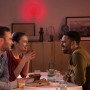 Szene mit Philips Hue Sana Wandleuchte in Weiß mit rotem Licht, umgeben von Menschen.