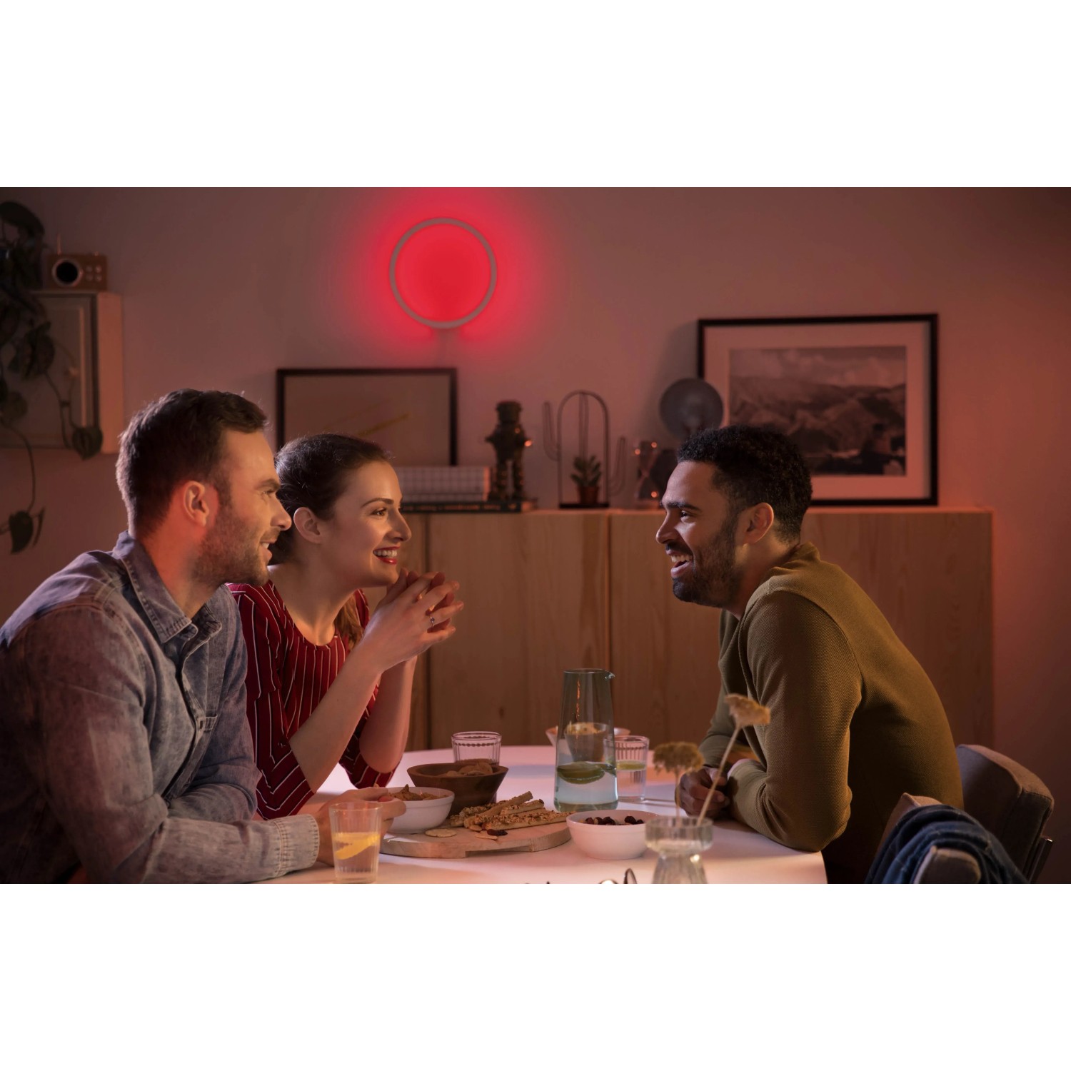 Szene mit Philips Hue Sana Wandleuchte in Weiß mit rotem Licht, umgeben von Menschen.