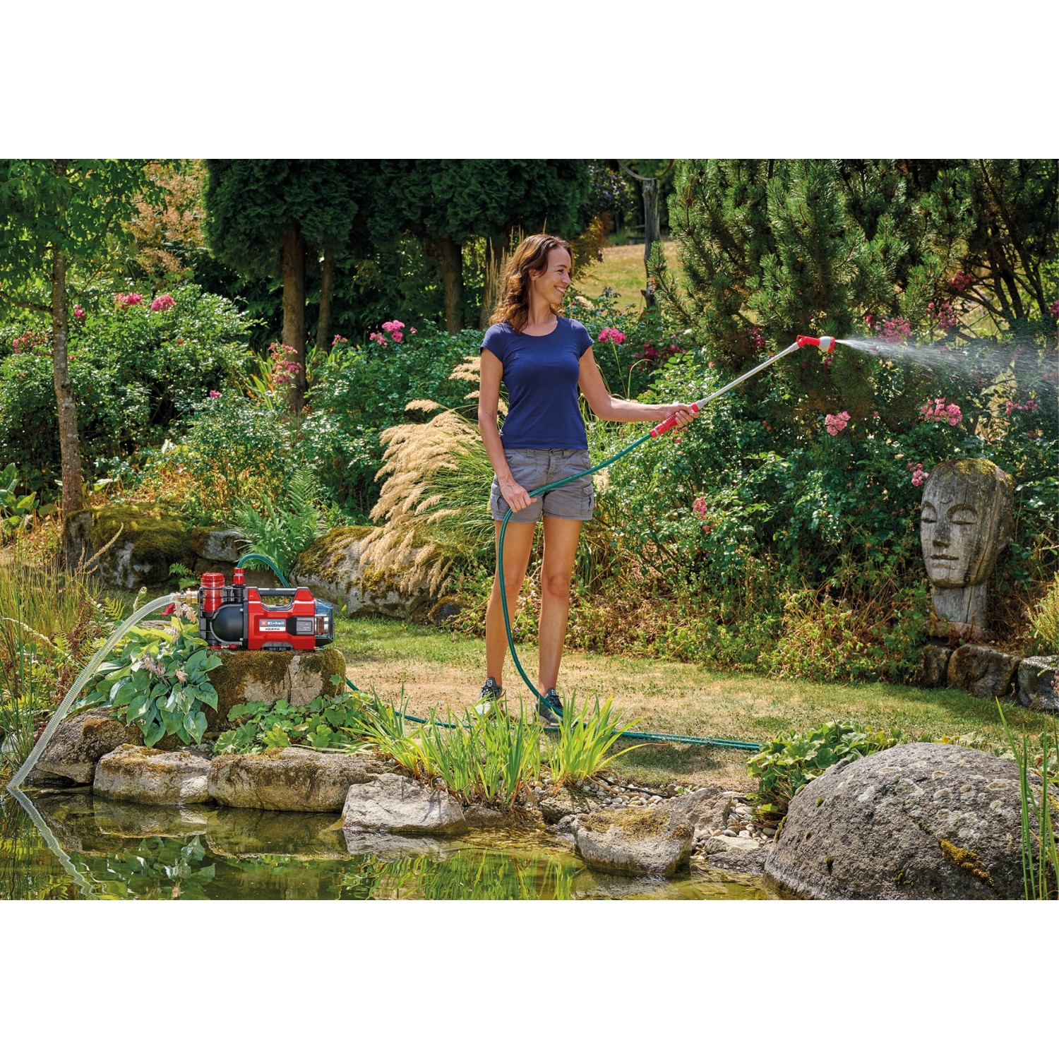 Einhell Aquinna 18/30 Akku-Wasserpumpe im Einsatz: Frau bewässert Garten mit Gartenschlauch.