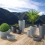 Scheurich Wave Globe Pflanzschalen in verschiedenen Größen und Farben auf einer Holzterrasse.