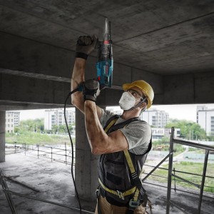 Arbeiter bohrt mit Bosch Professional Bohrhammer GBH 2-21 in Betondecke. Blauer Hammerbohrer für Bohren & Meißeln.