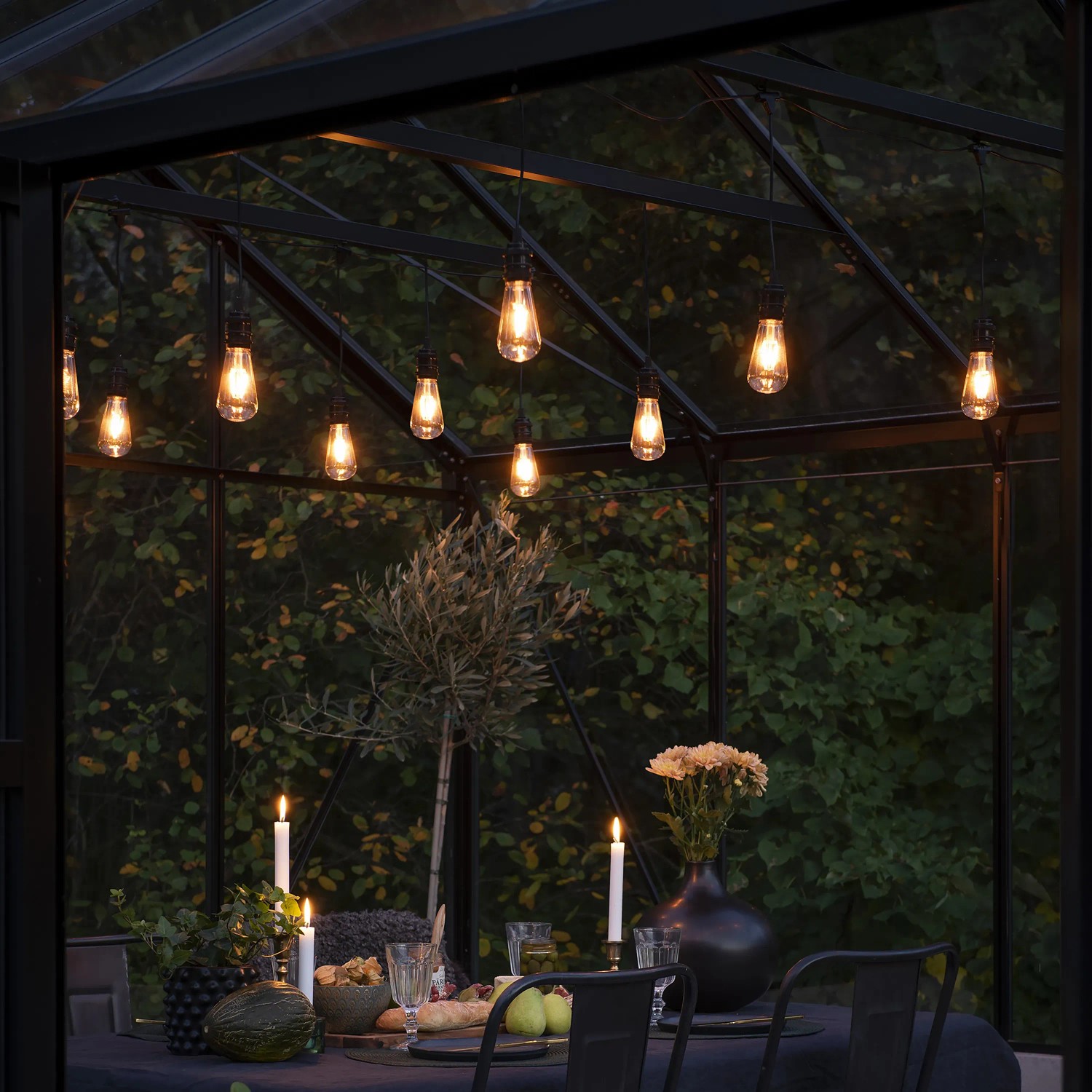 Konstsmide LED-Lichterkette Outdoor Retro mit 10 bernsteinfarbenen LEDs über gedecktem Tisch.