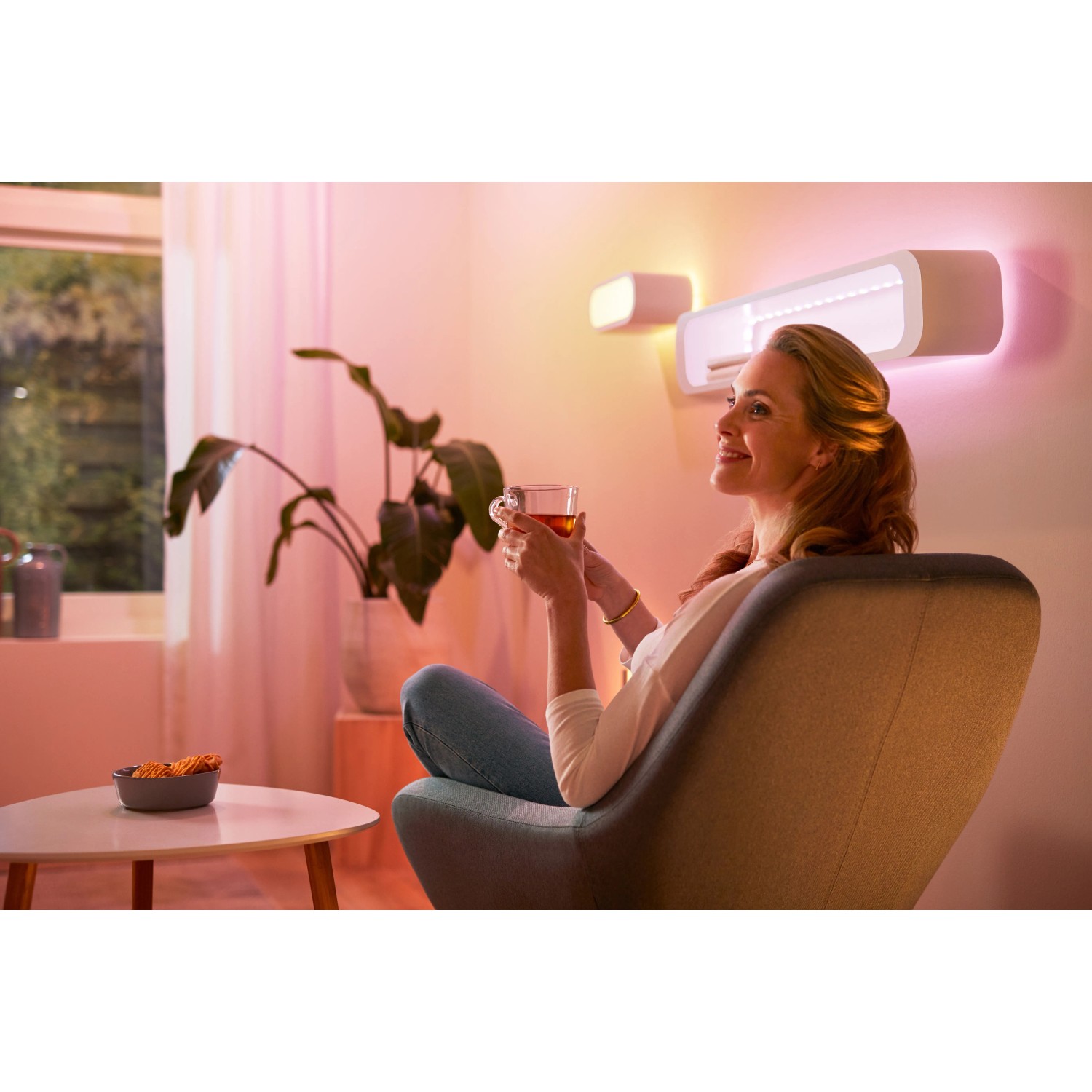 Frau entspannt mit WiZ LED Strip (Tunable White & Color) im Wohnzimmer.