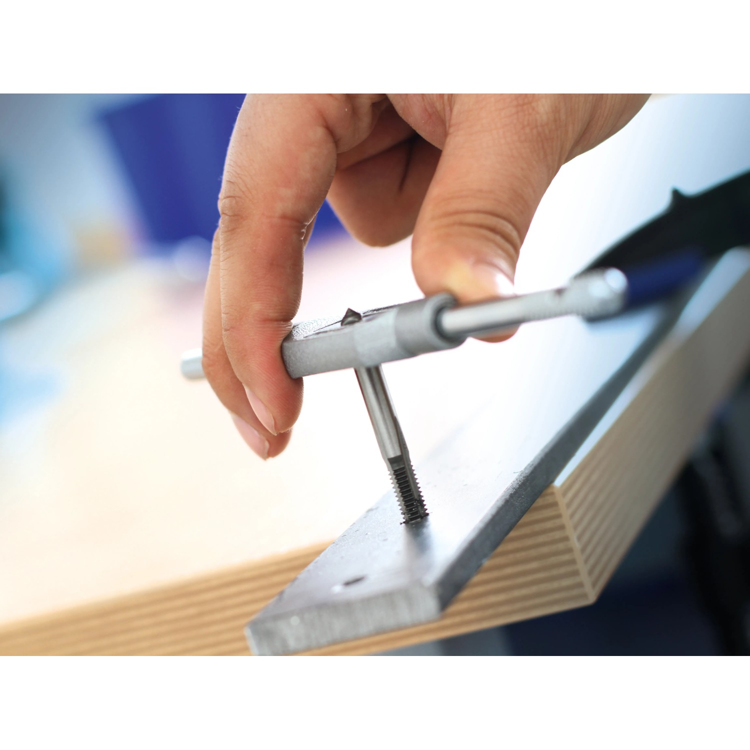 LUX Gewindebohrer-Set Comfort M4-M10 im Einsatz: Hand schneidet Gewinde in Metall.