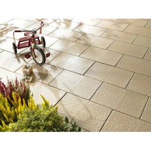 Verlegte Kann Terrassenplatte Sincera Creme 60x40 cm mit Kinderspielzeug und Pflanzen.
