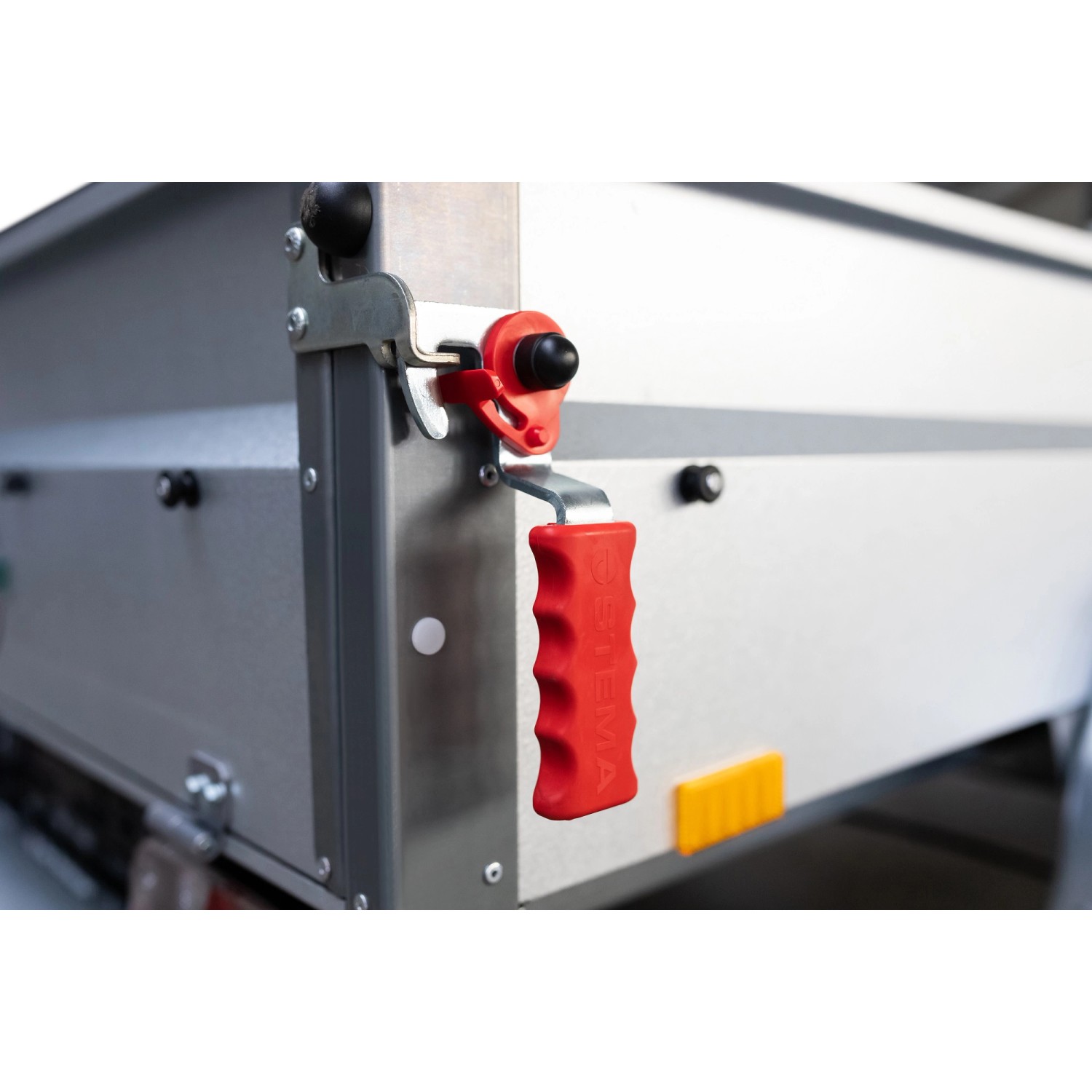 Detailansicht Stema Anhänger Basic 750: Roter Hebelverschluss an grauer Bordwand.