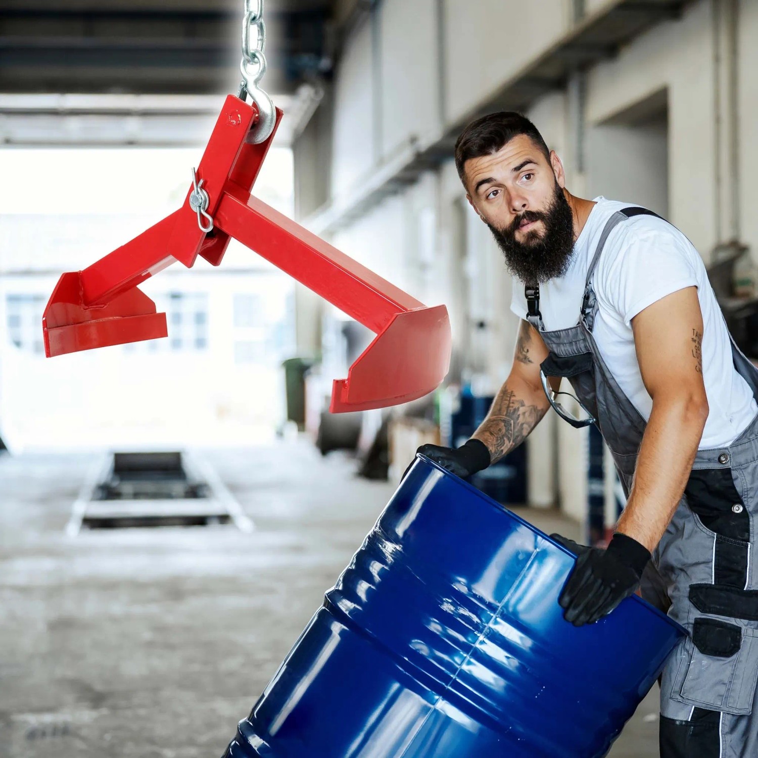 Rote Xpotool Hebeklemme über blauem 210L Fass, Arbeiter positioniert es. Vertikale Fasszange bis 500kg.